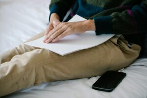 un aveugle lisant un courrier en braille avec son téléphone posé à côté de lui.